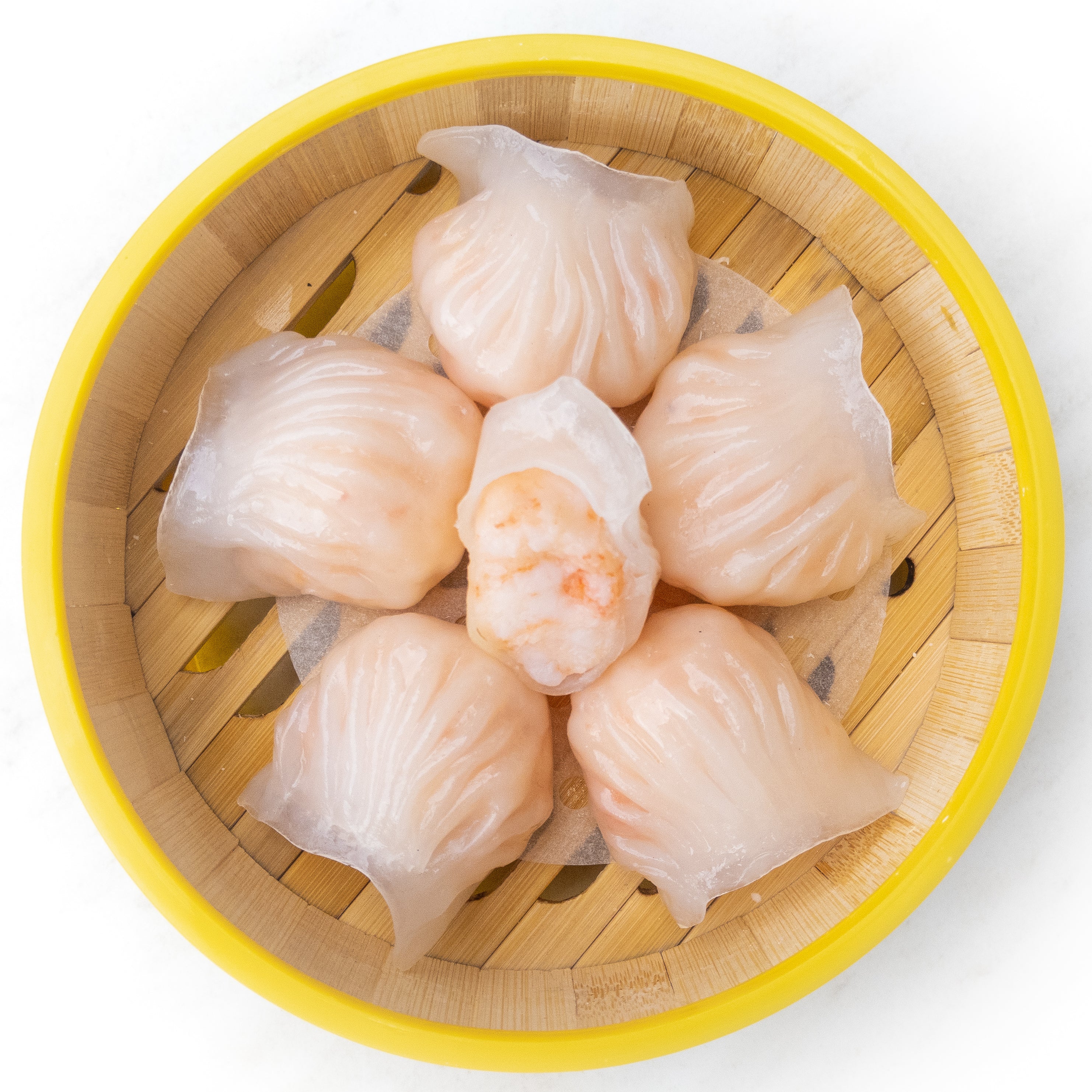 Har gow prawn dumplings in a yellow bamboo basket